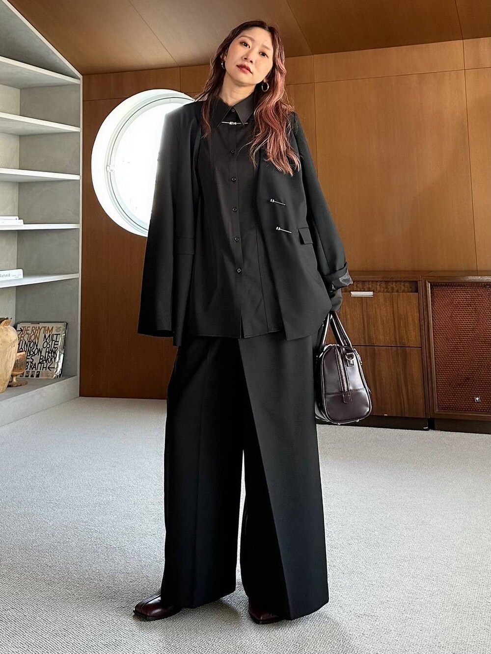 ブラウン系のボストンバッグ、レッド系のブーツを着用したレディースの秋コーディネートの3枚目の写真