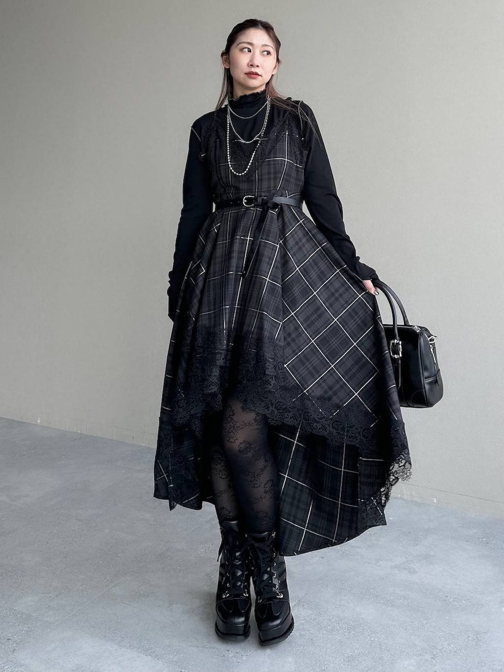 ブラック系のボストンバッグ、ブラック系のワンピース、ブラック系のブーツを着用したレディースの秋コーディネートの8枚目の写真