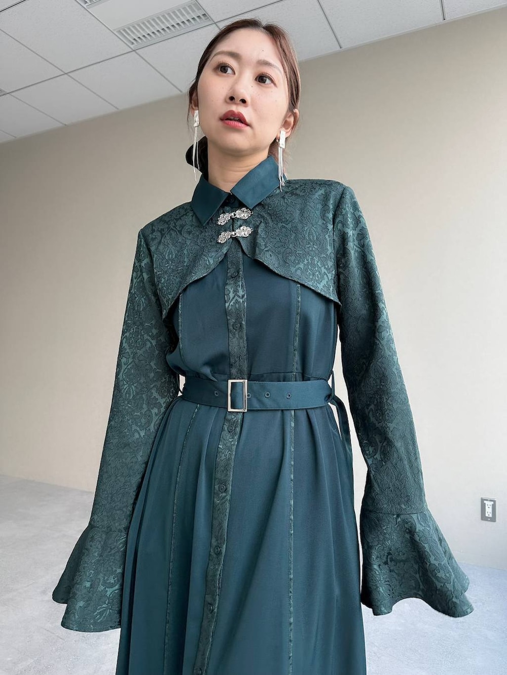 シルバー系のブーツ、グリーン系のワンピース、シルバー系のイヤリングを着用したレディースの秋コーディネートの3枚目の写真