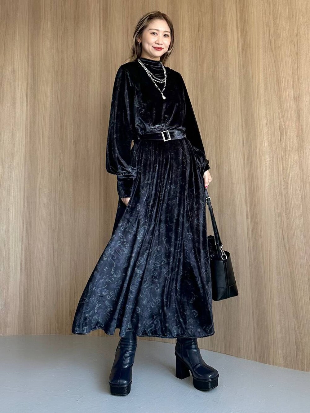 グレー系のワンピース、ブルー系のブーツ、ブラック系のショルダーバッグを着用したレディースの秋コーディネートの7枚目の写真