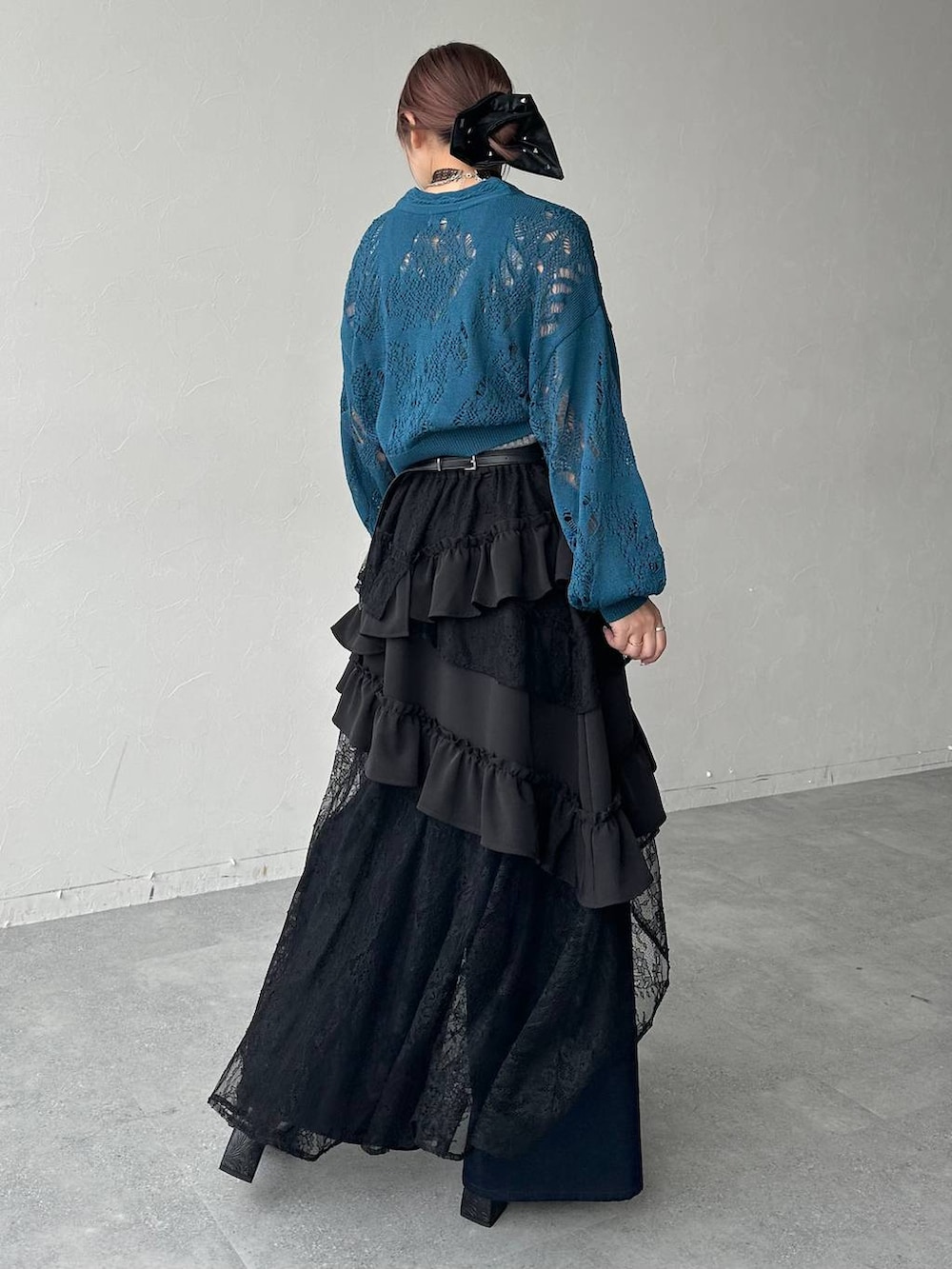 ブラック系のスカート、ブラック系のサンダル、ブルー系のデニムパンツを着用したレディースの春コーディネートの3枚目の写真