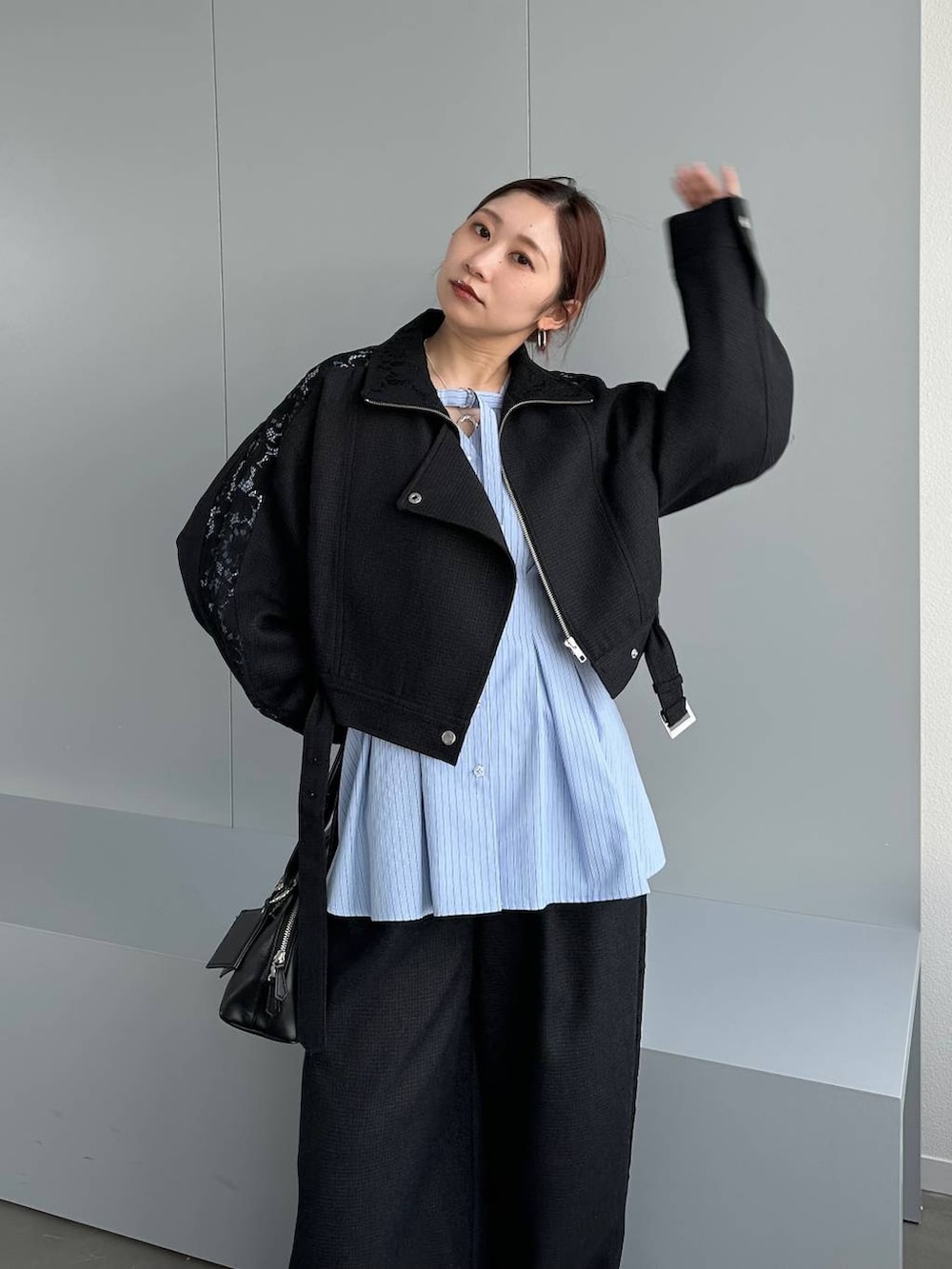 ブラック系のハンドバッグ、ブラック系のスラックス、ブラック系のブルゾンを着用したレディースの春コーディネートの4枚目の写真
