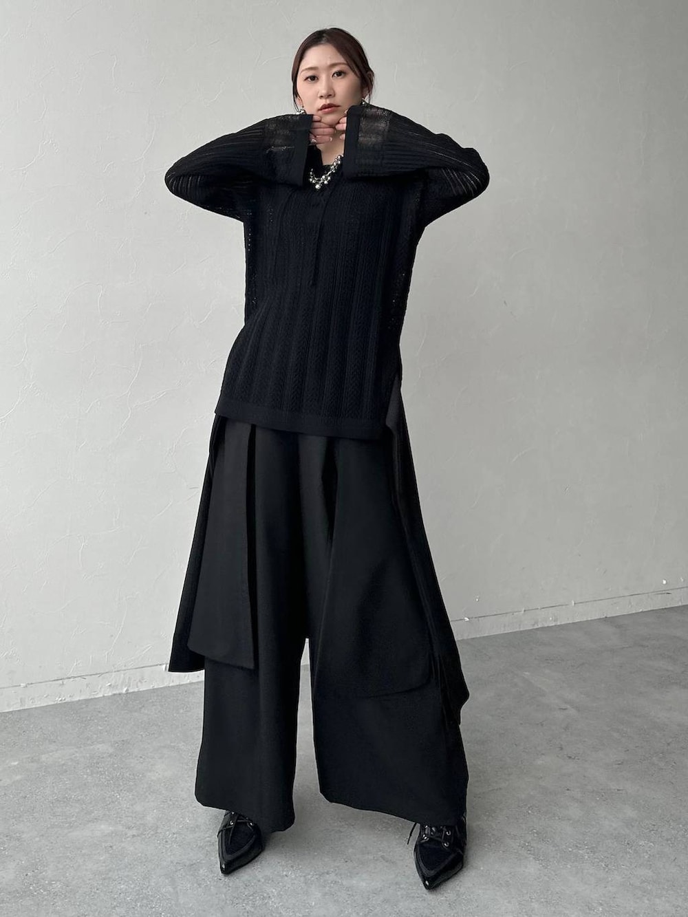 ブラック系のサンダル、ブラック系のニット/セーター、ブラック系のスラックスを着用したレディースの春コーディネートの5枚目の写真