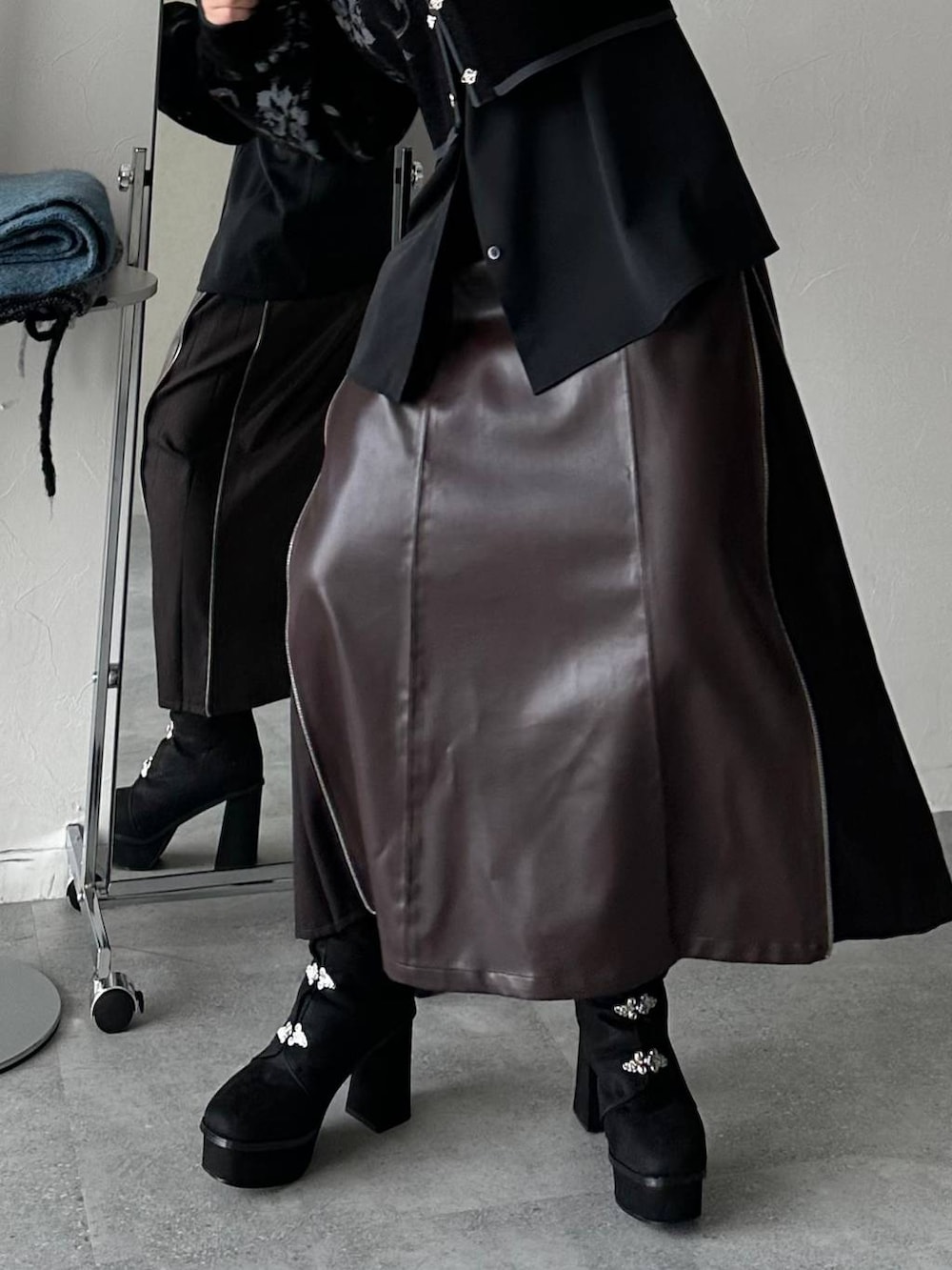 ブラウン系のスカート、ブラック系のブーツを着用したレディースの秋コーディネートの2枚目の写真