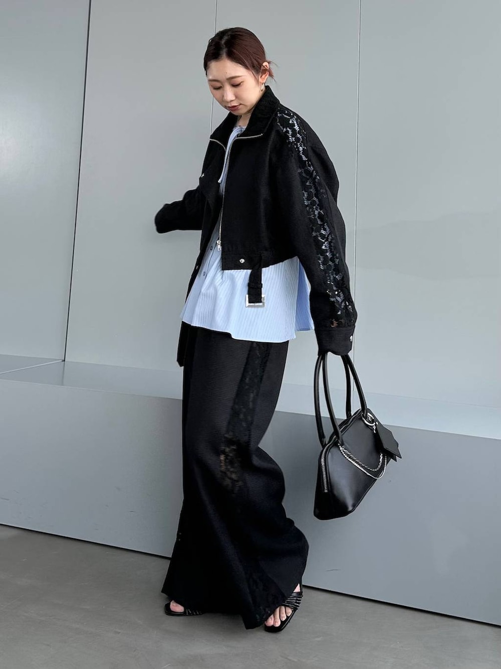 ブラック系のハンドバッグ、ブラック系のスラックス、ブラック系のブルゾンを着用したレディースの春コーディネートの2枚目の写真