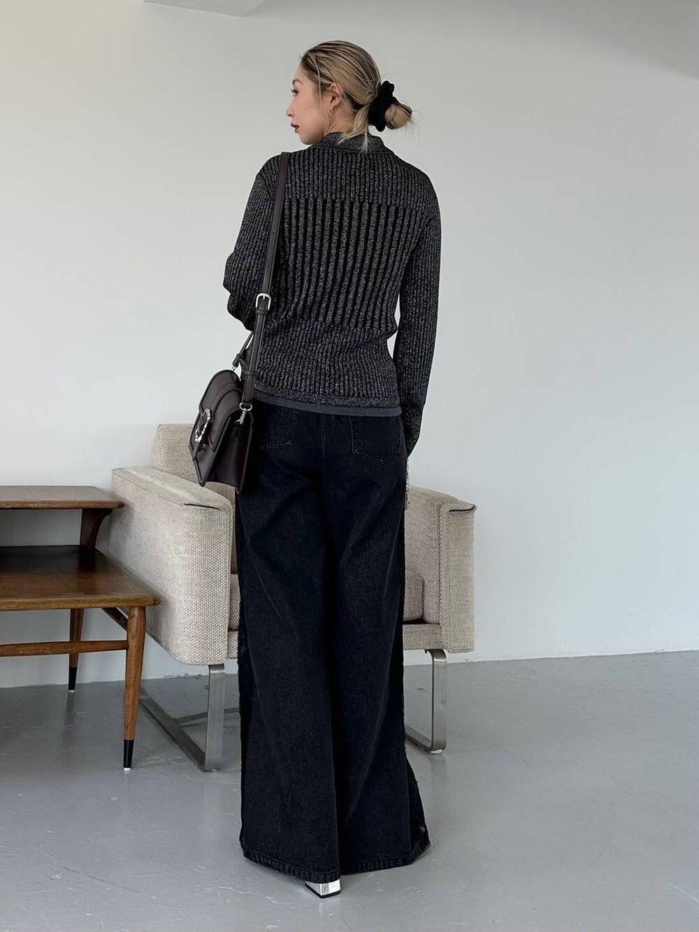 ブラック系のショルダーバッグ、ブラック系のデニムパンツ、ブラック系のブーツを着用したレディースの秋コーディネートの2枚目の写真