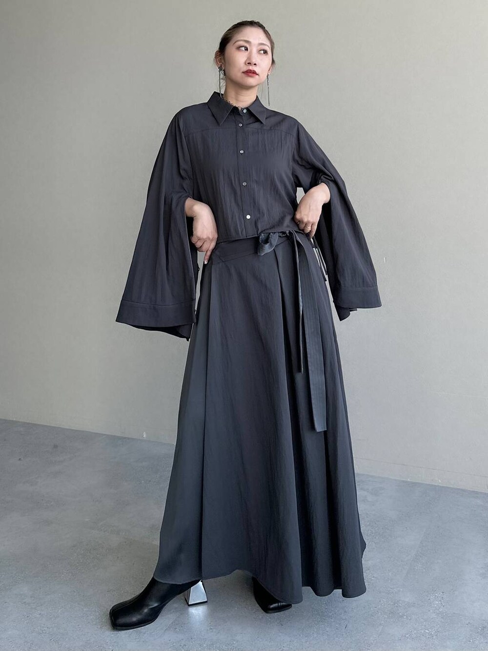 ブラック系のブーツ、グレー系のスカート、グレー系のシャツ/ブラウスを着用したレディースの秋コーディネートの7枚目の写真