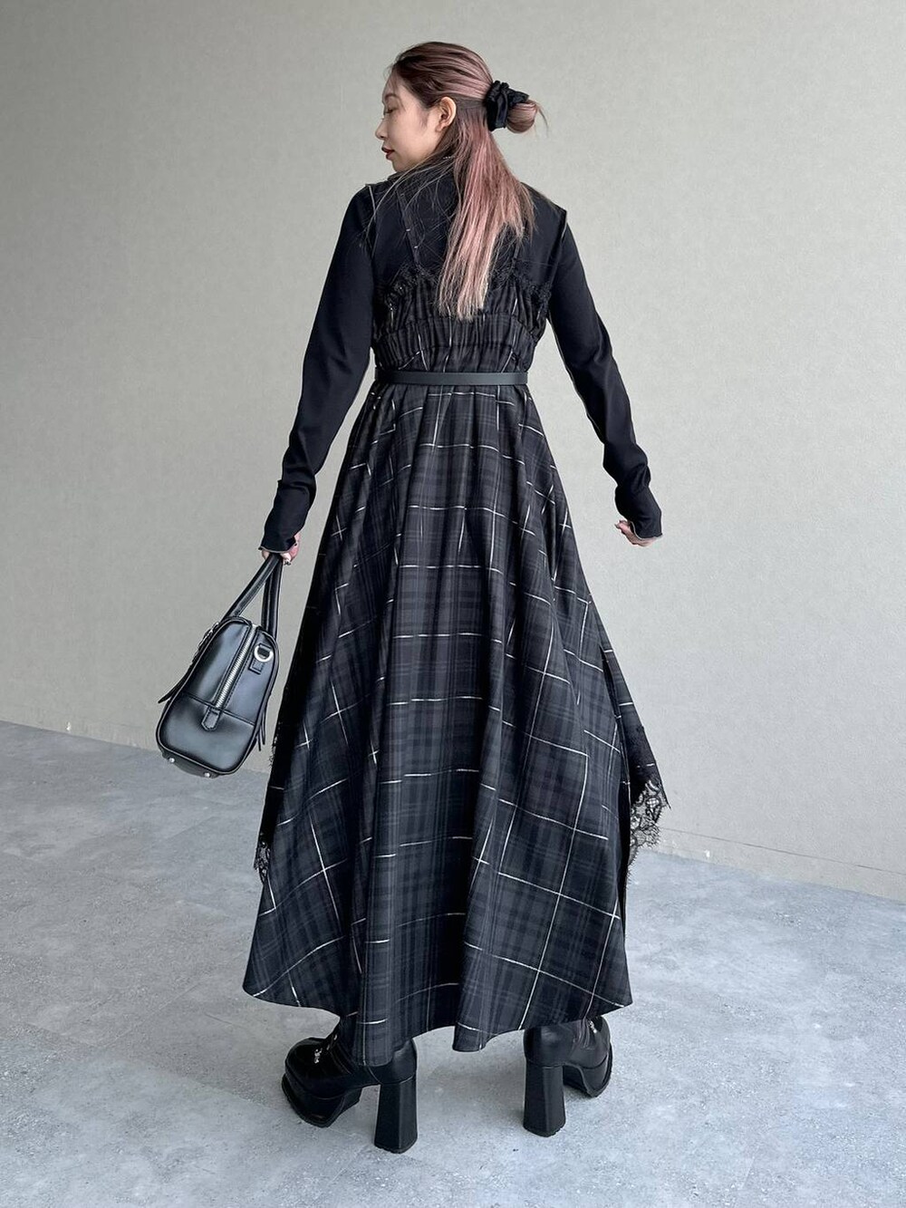 ブラック系のボストンバッグ、ブラック系のワンピース、ブラック系のブーツを着用したレディースの秋コーディネートの2枚目の写真