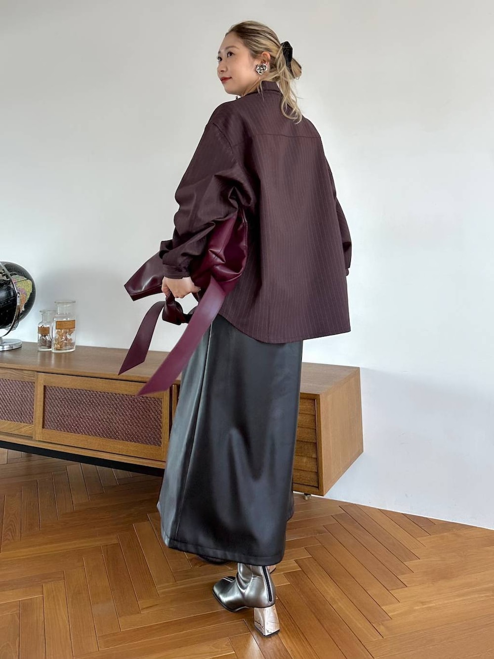 レッド系のトートバッグ、ブラック系のスカート、シルバー系のブーツを着用したレディースの夏コーディネートの2枚目の写真