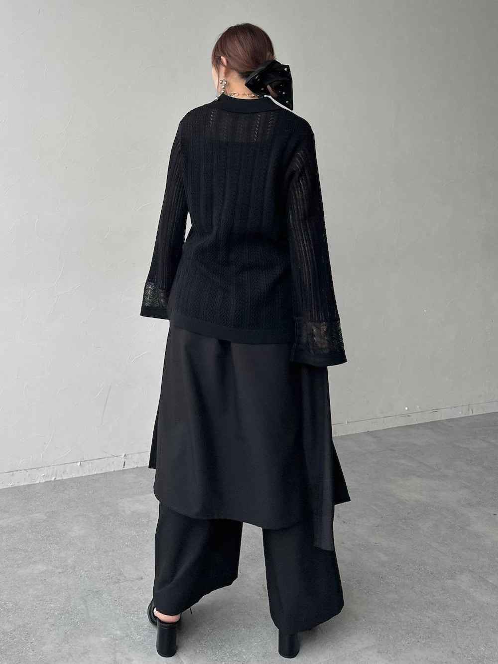 ブラック系のサンダル、ブラック系のニット/セーター、ブラック系のスラックスを着用したレディースの春コーディネートの2枚目の写真