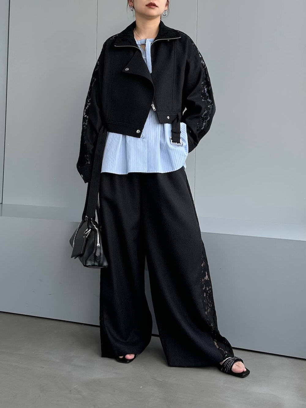 ブラック系のハンドバッグ、ブラック系のスラックス、ブラック系のブルゾンを着用したレディースの春コーディネートの7枚目の写真