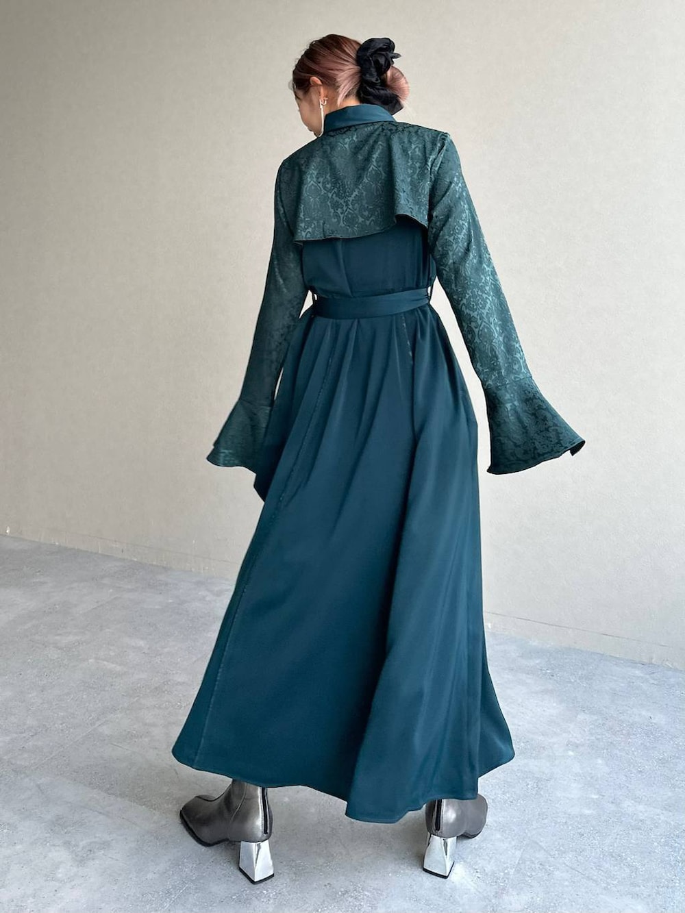 シルバー系のブーツ、グリーン系のワンピース、シルバー系のイヤリングを着用したレディースの秋コーディネートの2枚目の写真