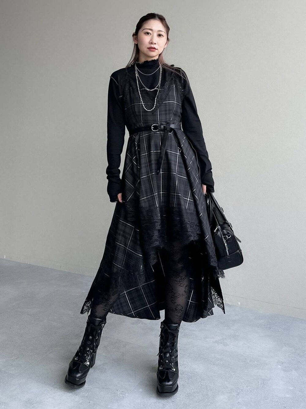 ブラック系のボストンバッグ、ブラック系のワンピース、ブラック系のブーツを着用したレディースの秋コーディネートの9枚目の写真