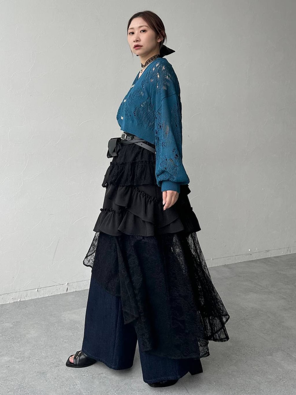 ブラック系のスカート、ブラック系のサンダル、ブルー系のデニムパンツを着用したレディースの春コーディネートの2枚目の写真