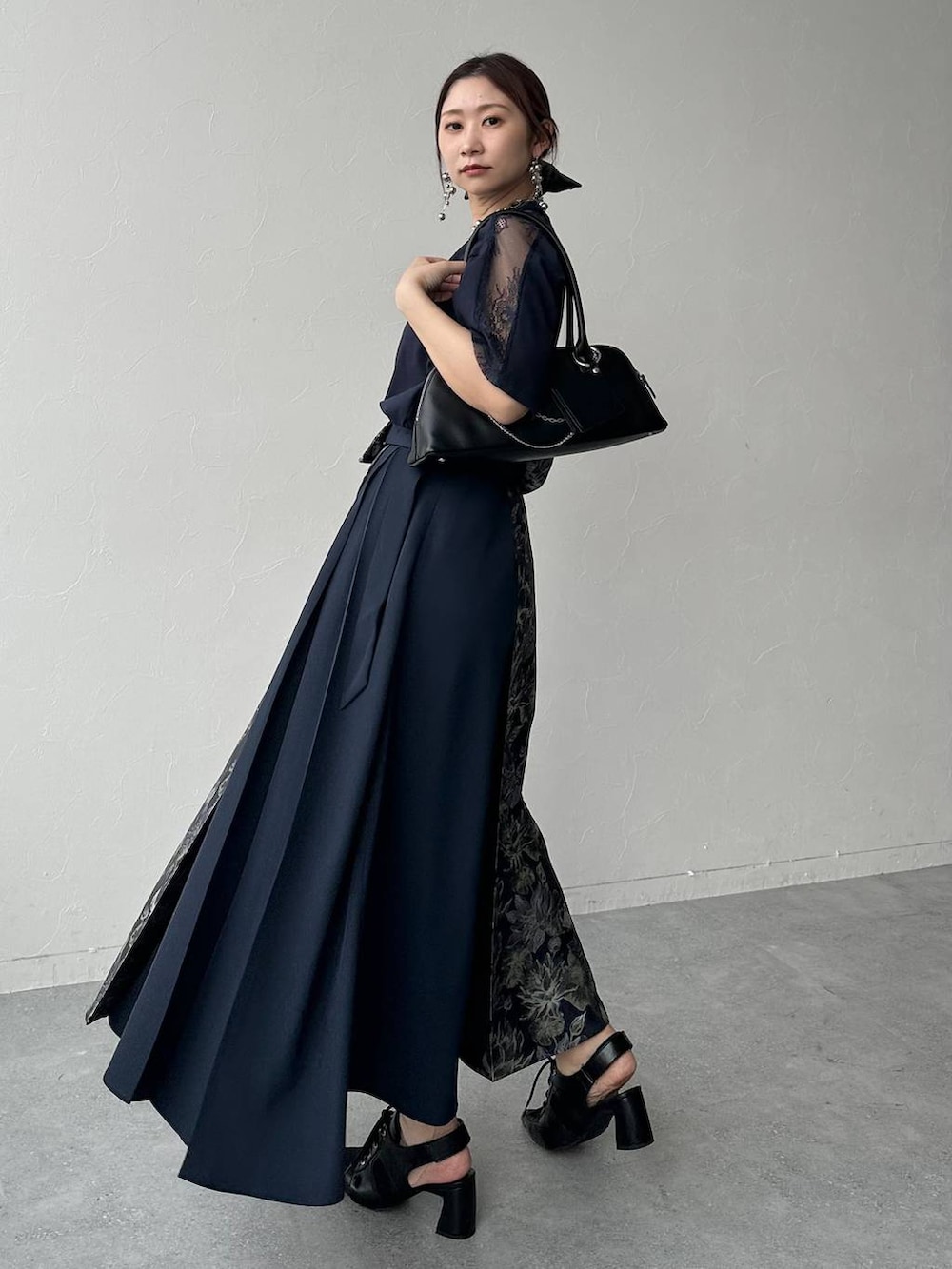 ブラック系のサンダル、ブラック系のハンドバッグ、ブルー系のスカートを着用したレディースの春コーディネートの2枚目の写真