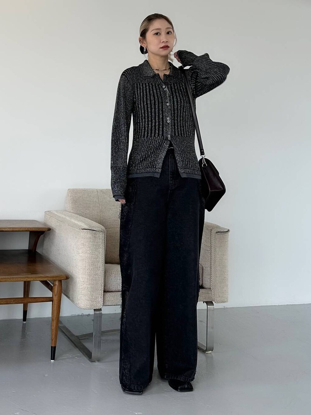 ブラック系のショルダーバッグ、ブラック系のデニムパンツ、ブラック系のブーツを着用したレディースの秋コーディネートの9枚目の写真