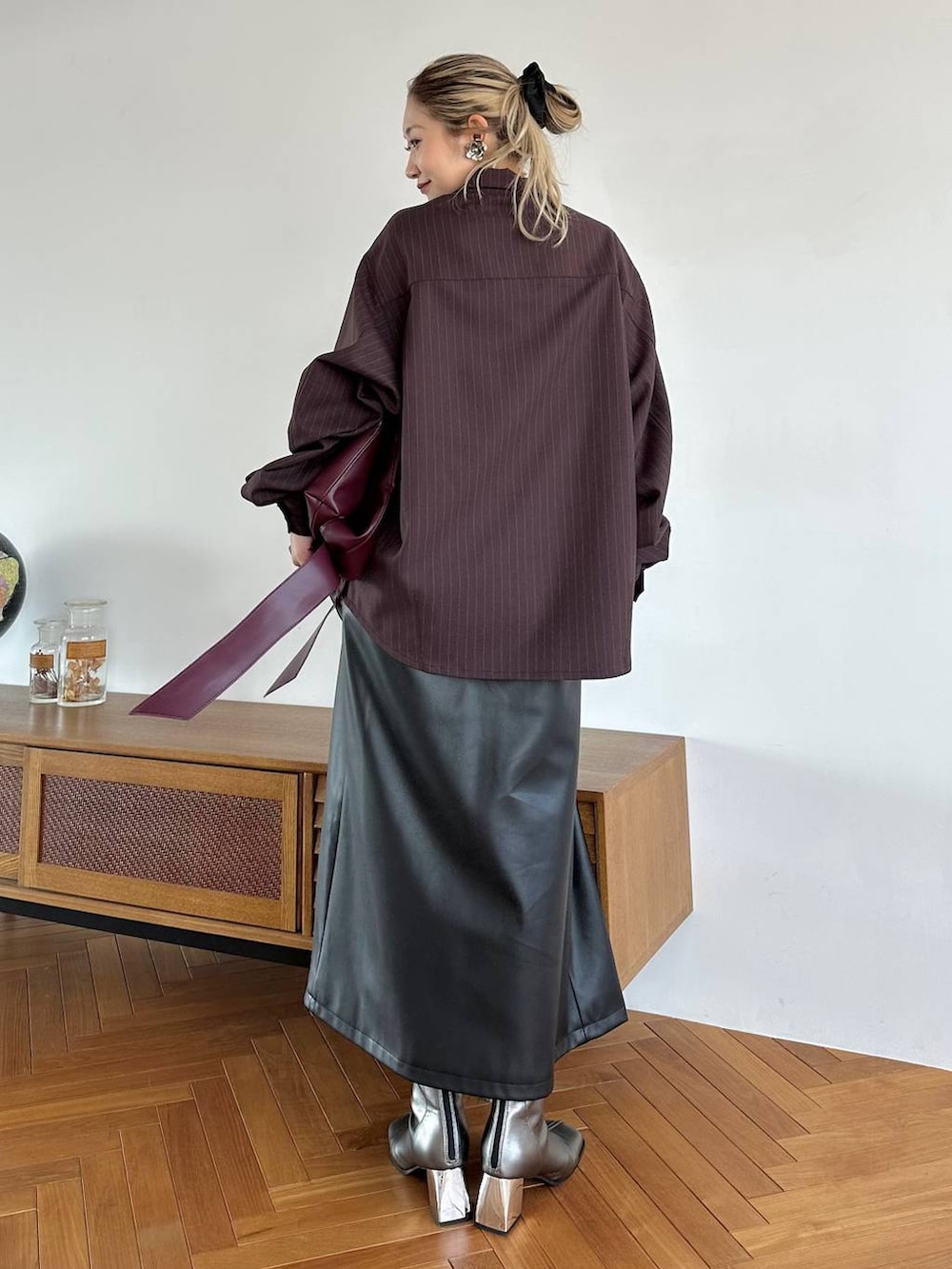 レッド系のトートバッグ、ブラック系のスカート、シルバー系のブーツを着用したレディースの夏コーディネートの3枚目の写真