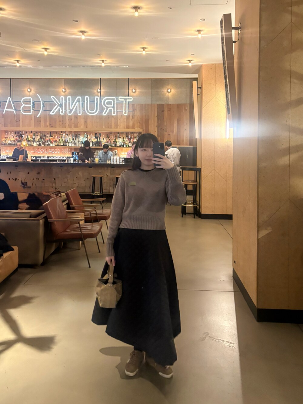 ベージュ系のニット/セーター、ブラック系のスカート、ベージュ系のスニーカーを着用したレディースの冬コーディネートの2枚目の写真