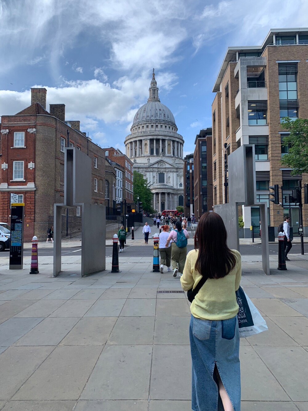 イエロー系のニット/セーター、ブラック系のバッグ、ブルー系のデニムスカートを着用したレディースの秋コーディネートの2枚目の写真