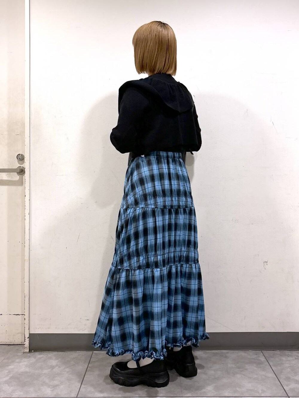 ブラック系のニット/セーター、ブルー系のスカート、ブラック系のスニーカーを着用したレディースの秋コーディネートの3枚目の写真