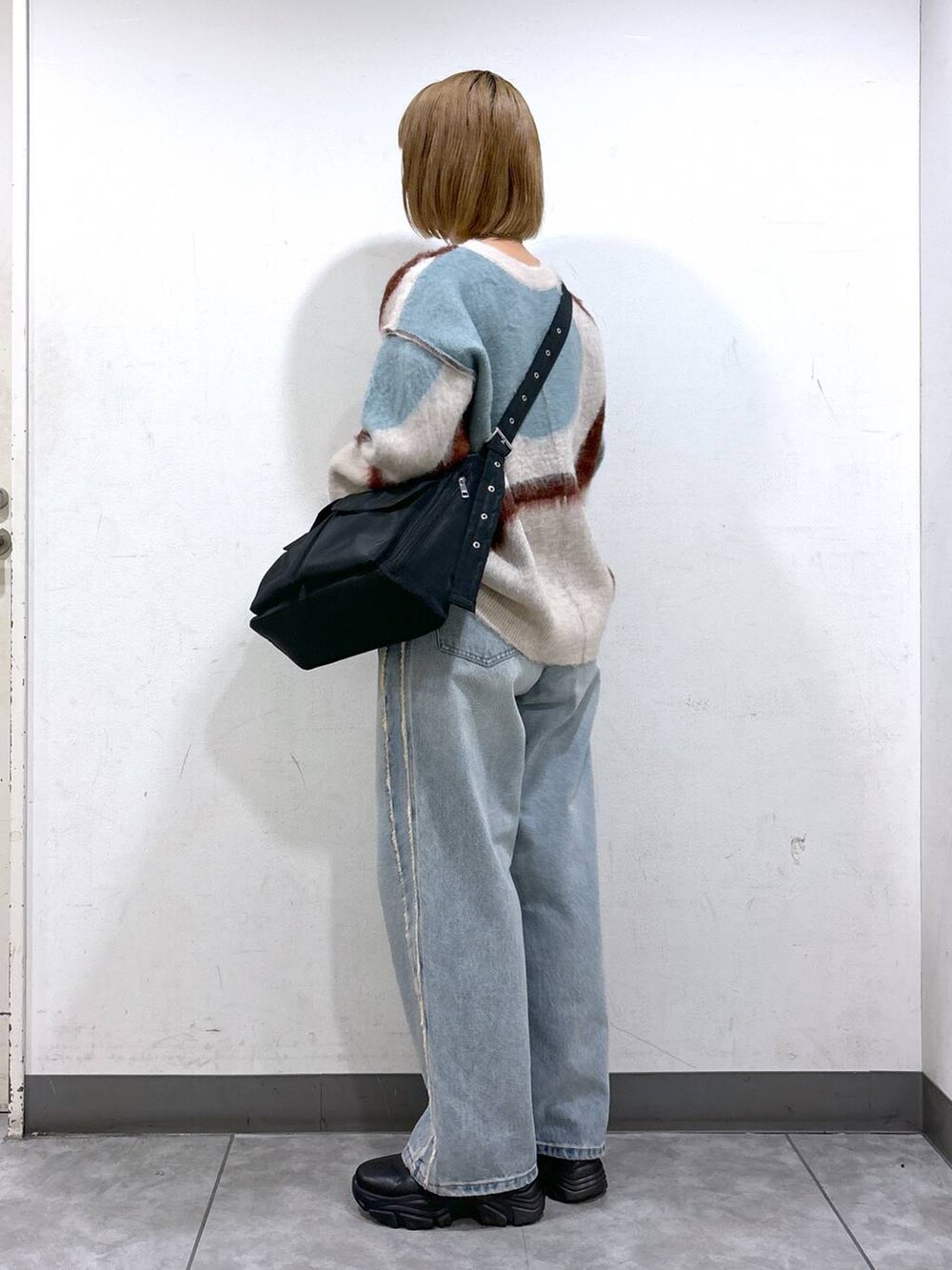 ブルー系のデニムパンツ、ブラック系のブーツ、ブラック系のショルダーバッグを着用したレディースの秋コーディネートの3枚目の写真