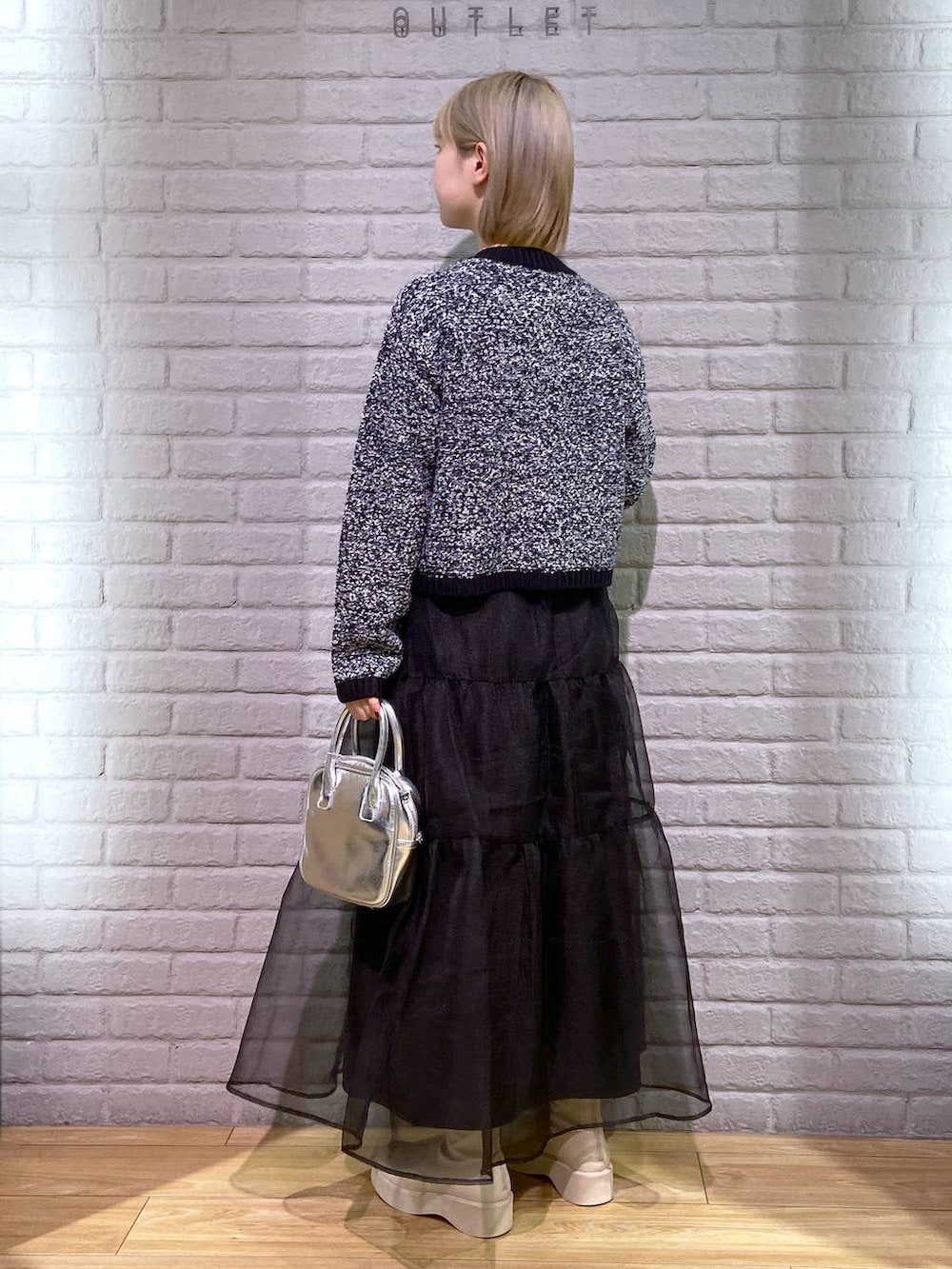 ホワイト系のブーツ、ブラック系のカーディガン/ボレロ、ブラック系のスカートを着用したレディースの秋コーディネートの3枚目の写真