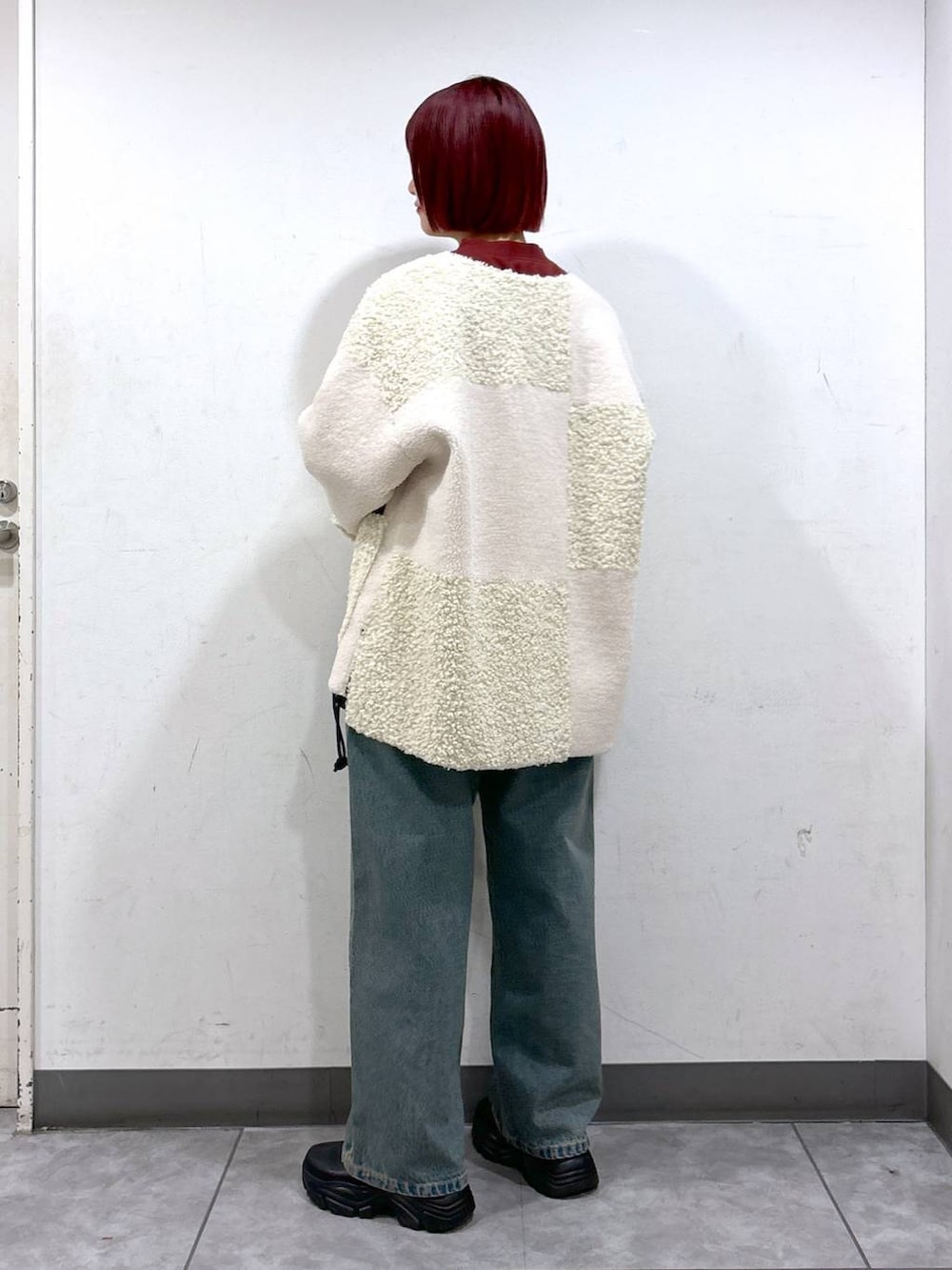 ブルー系のデニムパンツ、ブラック系のブーツ、ブラック系のショルダーバッグを着用したレディースの秋コーディネートの3枚目の写真