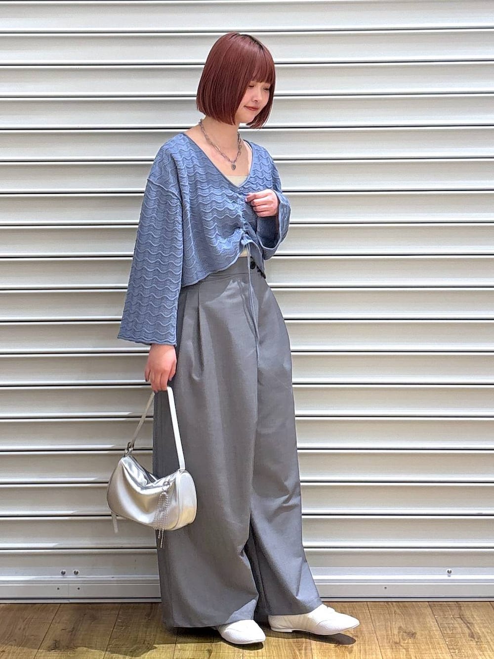 シルバー系のトートバッグ、ゴールド系のタンクトップ、ホワイト系のスニーカーを着用したレディースの春コーディネートの2枚目の写真