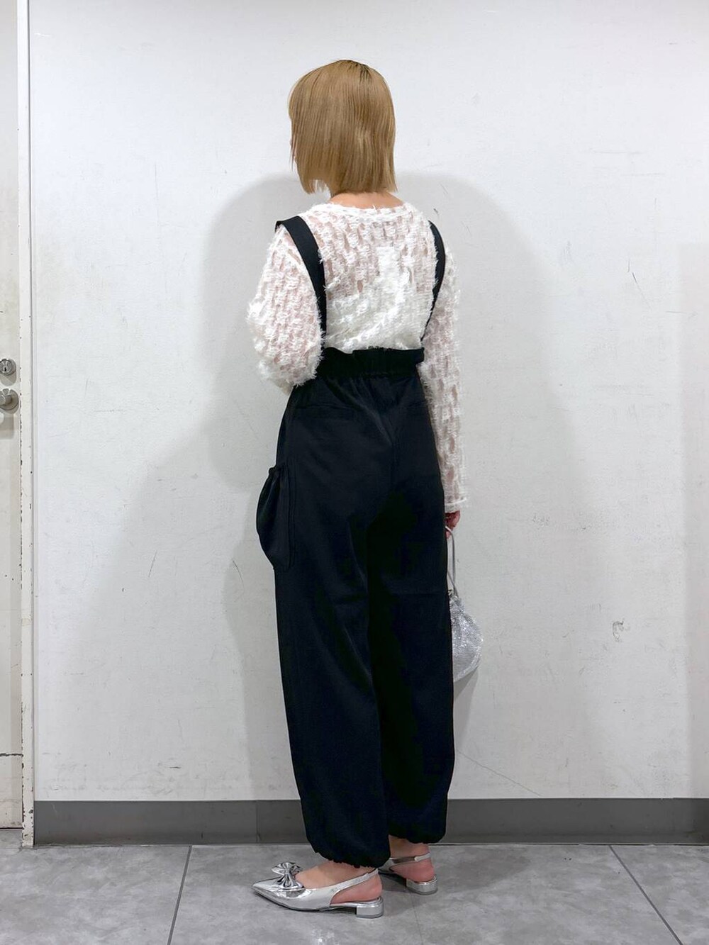 シルバー系のパンプス、ブラック系のワンピース、シルバー系のショルダーバッグを着用したレディースの秋コーディネートの3枚目の写真