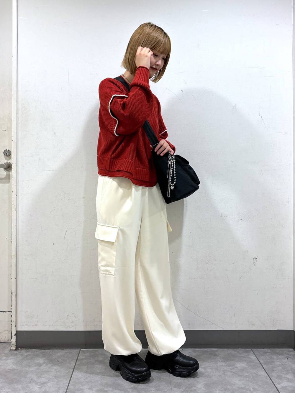 ホワイト系のニット/セーター、ブラック系のブーツ、ホワイト系のショルダーバッグを着用したレディースの秋コーディネートの2枚目の写真