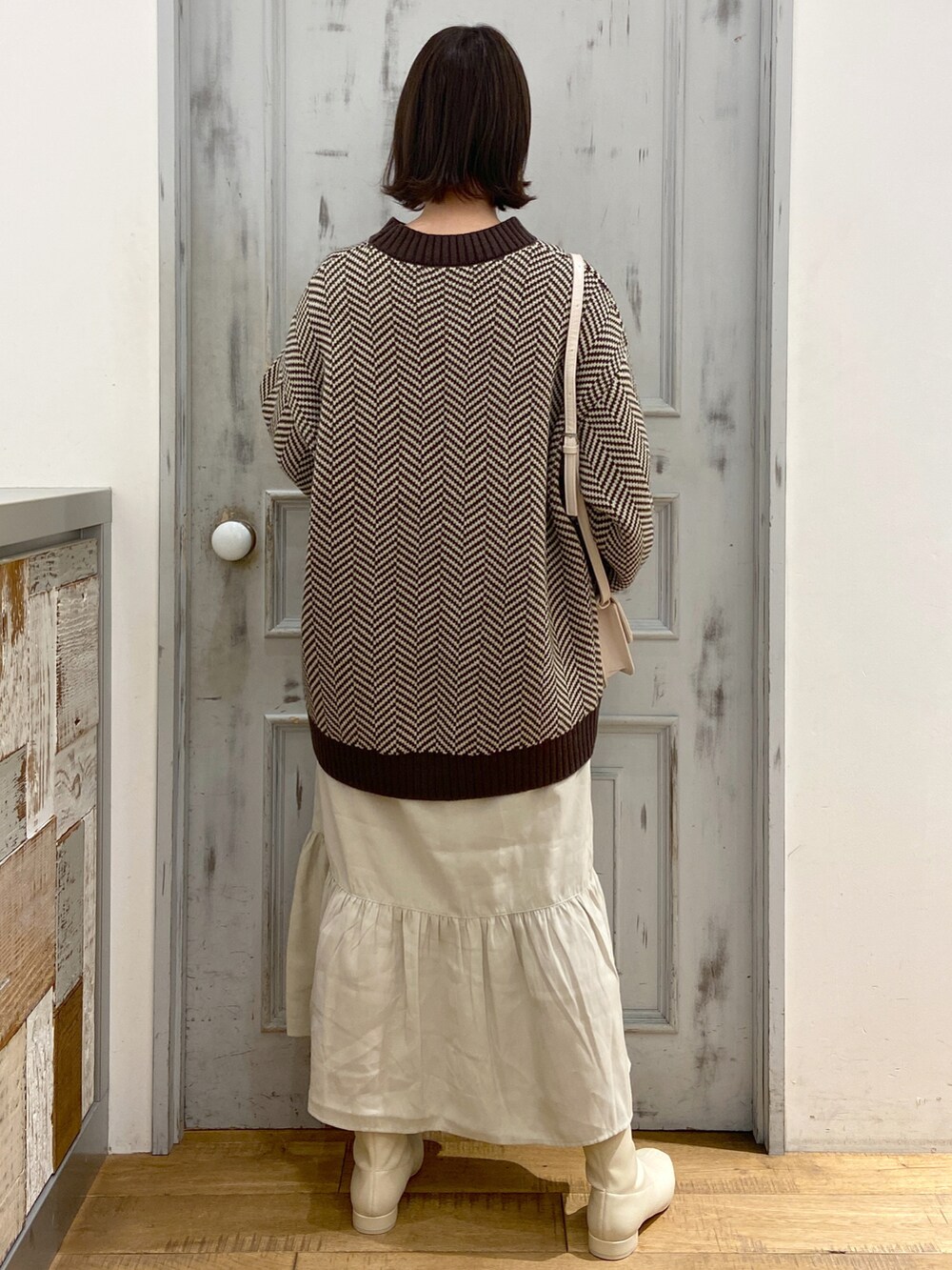 ブラウン系のワンピース、ホワイト系のショルダーバッグ、ホワイト系のブーツを着用したレディースの冬コーディネートの3枚目の写真