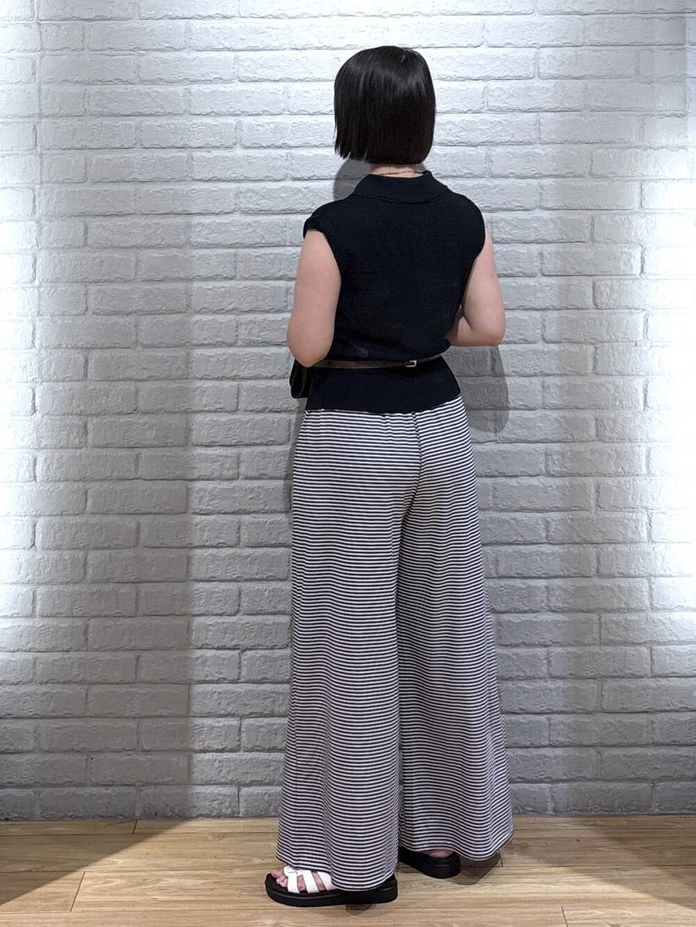 ブラック系のベスト、ホワイト系のその他パンツ、ホワイト系のサンダルを着用したレディースの夏コーディネートの3枚目の写真
