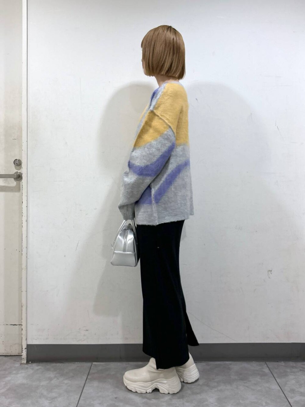 ブラック系のスカート、シルバー系のボストンバッグ、ホワイト系のブーツを着用したレディースの秋コーディネートの3枚目の写真