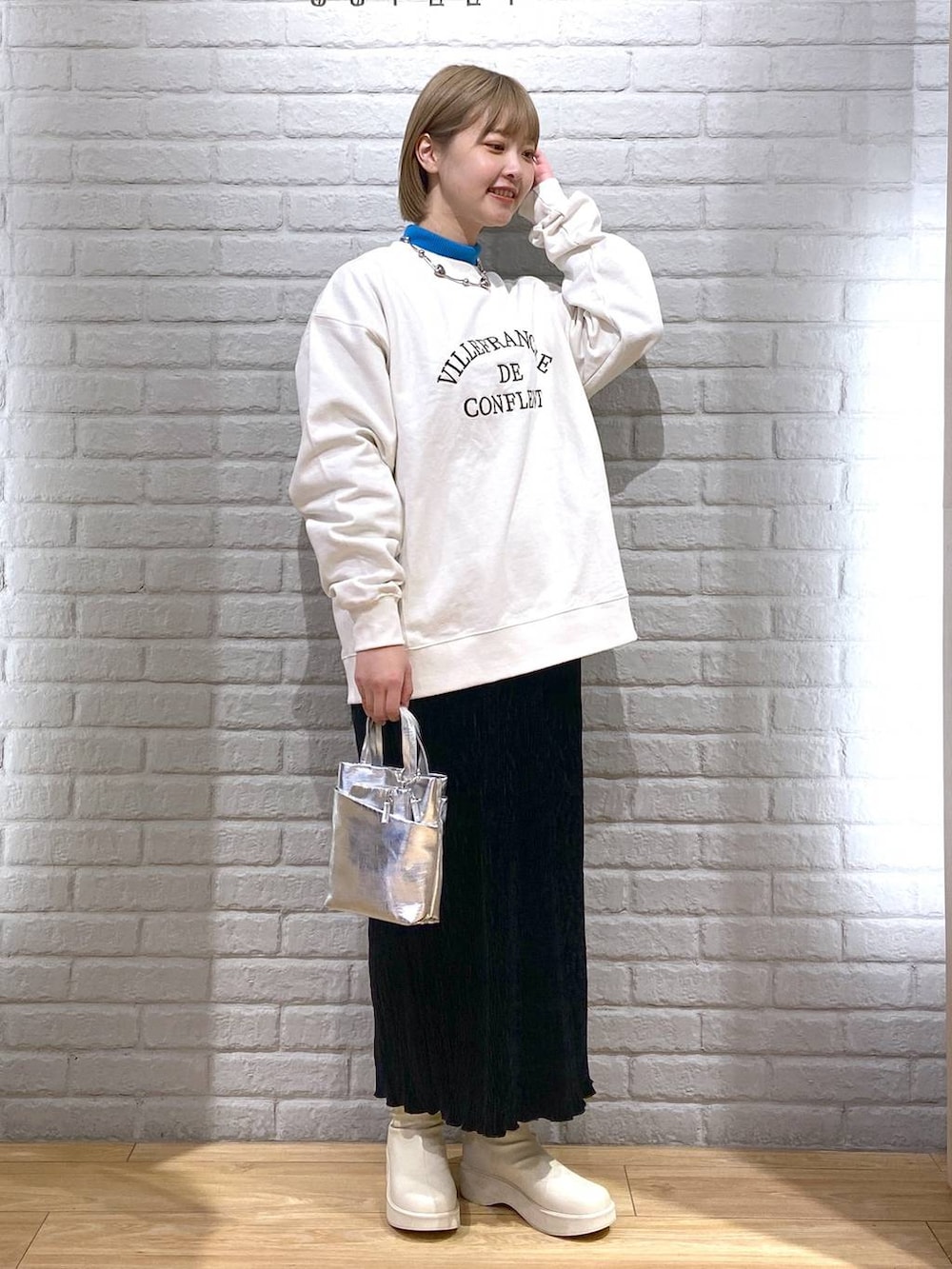 ホワイト系のスウェット、ブルー系のニット/セーター、ホワイト系のブーツを着用したレディースの冬コーディネートの2枚目の写真