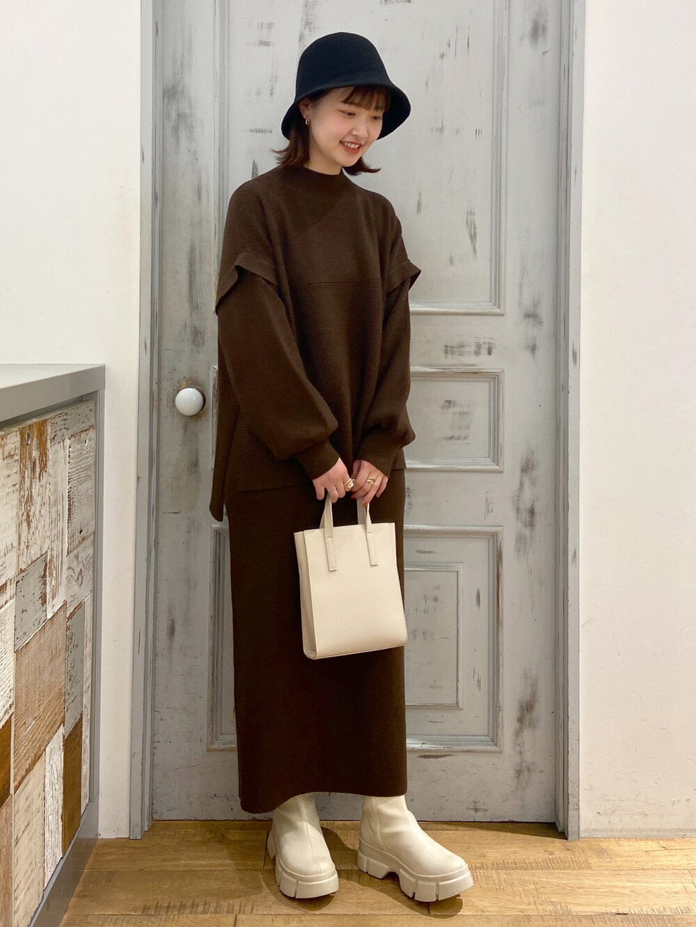ブラウン系のワンピース、ベージュ系のショルダーバッグ、ホワイト系のブーツを着用したレディースの冬コーディネートの2枚目の写真
