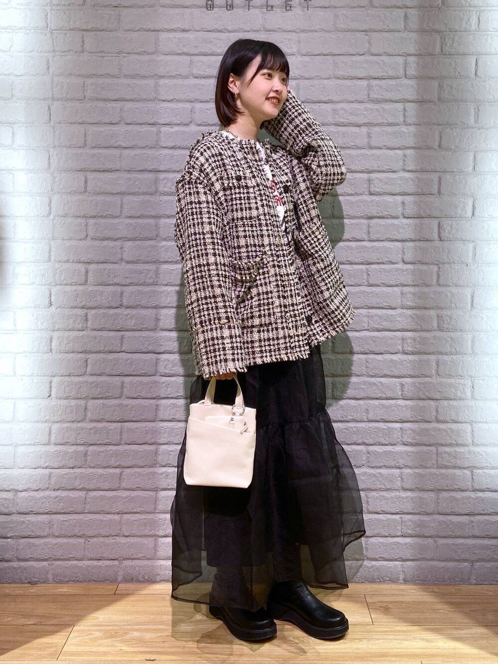 ブラウン系のノーカラージャケット、ブラック系のブーツ、ホワイト系のショルダーバッグを着用したレディースの秋コーディネートの2枚目の写真