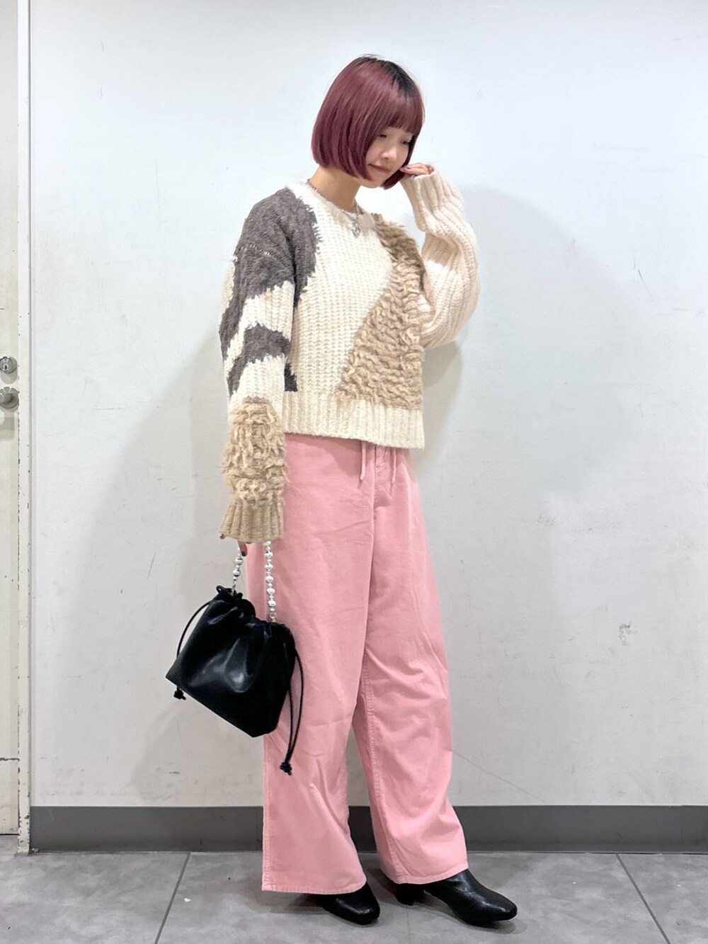 ブラック系のブーツ、ブラック系のニット/セーター、ブラック系のショルダーバッグを着用したレディースの冬コーディネートの2枚目の写真