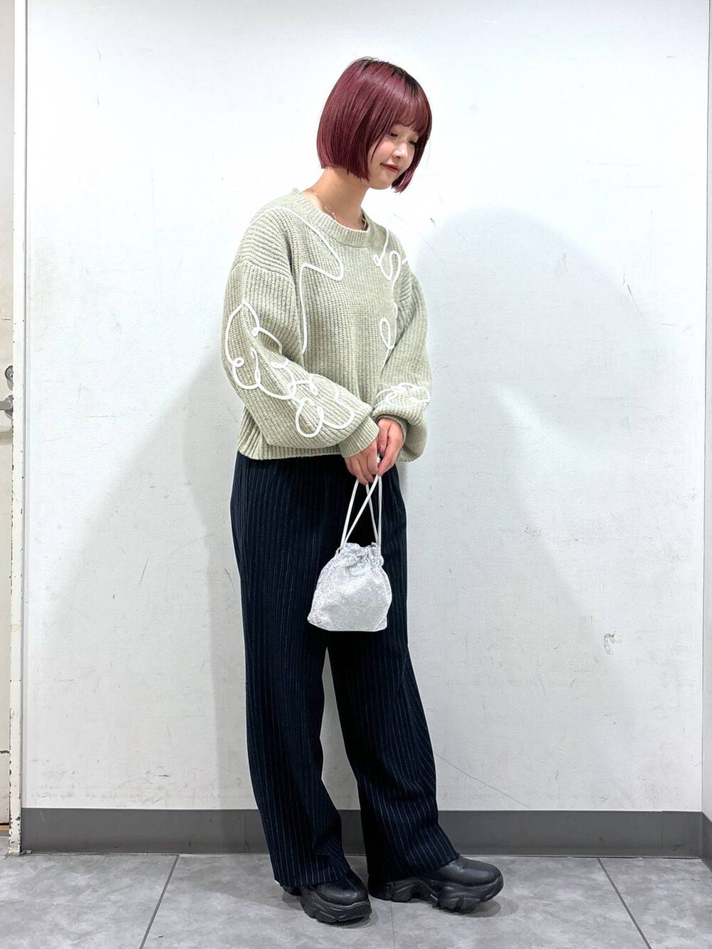 ブラック系のブーツ、シルバー系のショルダーバッグ、ブルー系のその他パンツを着用したレディースの秋コーディネートの2枚目の写真