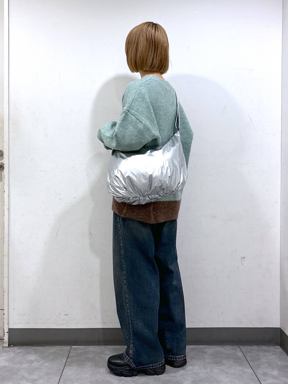 ブルー系のデニムパンツ、ブラック系のブーツ、グリーン系のニット/セーターを着用したレディースの秋コーディネートの2枚目の写真