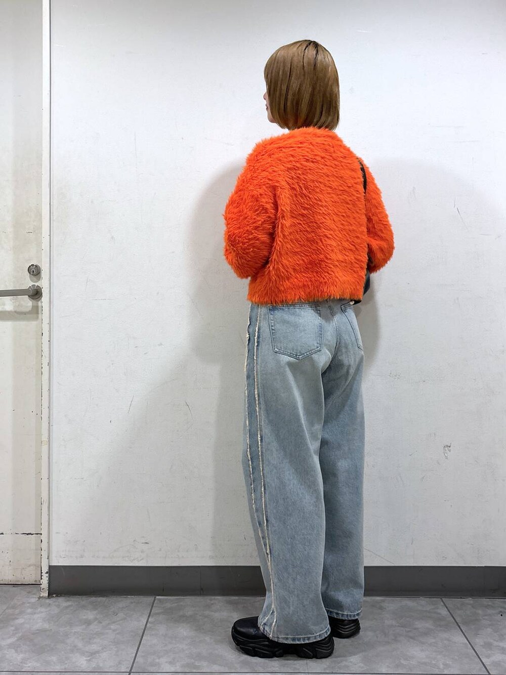 ブルー系のデニムパンツ、ブラック系のブーツ、ブラック系のショルダーバッグを着用したレディースの秋コーディネートの3枚目の写真