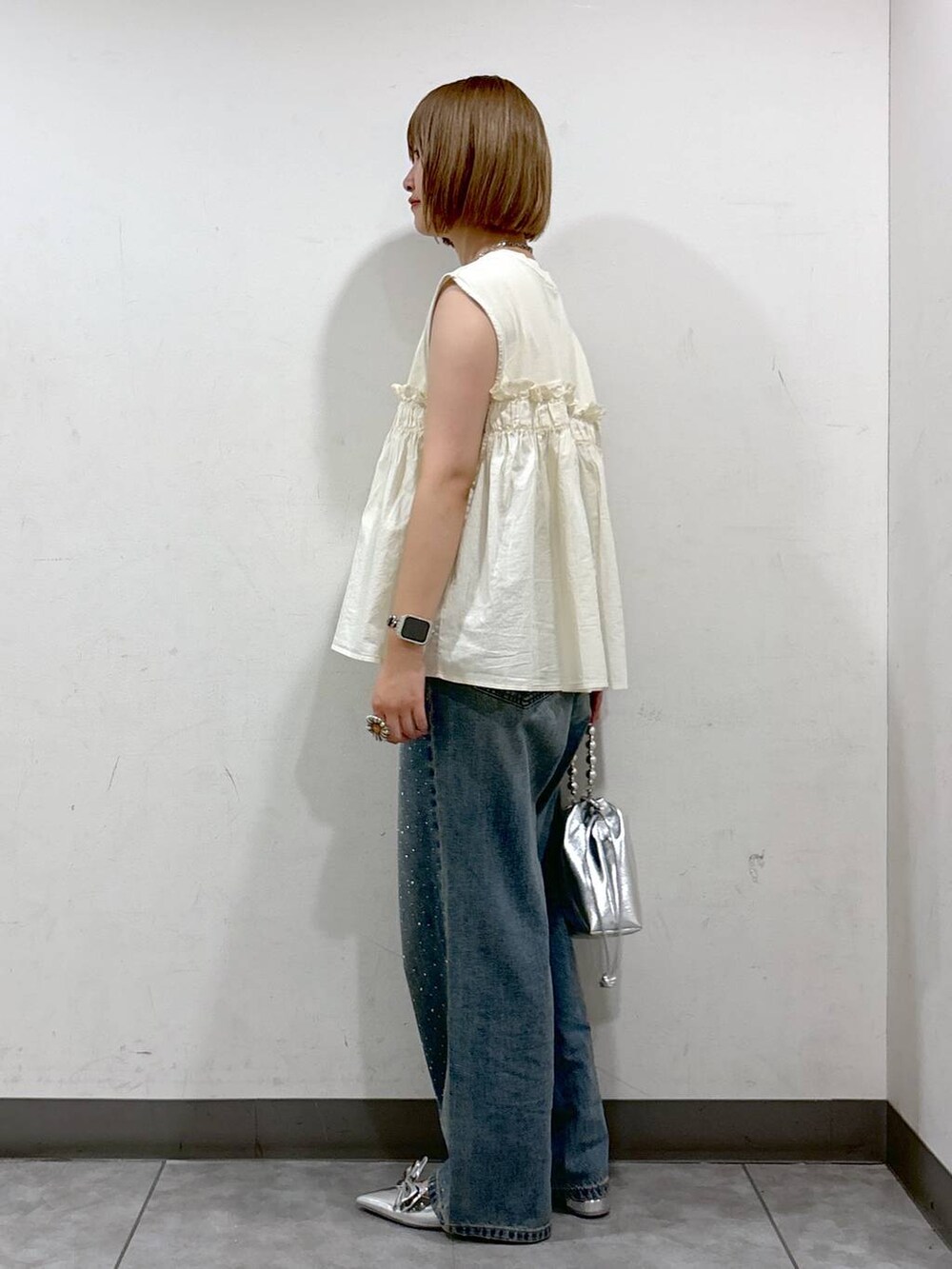 シルバー系のパンプス、シルバー系のショルダーバッグ、ブルー系のデニムパンツを着用したレディースの夏コーディネートの3枚目の写真