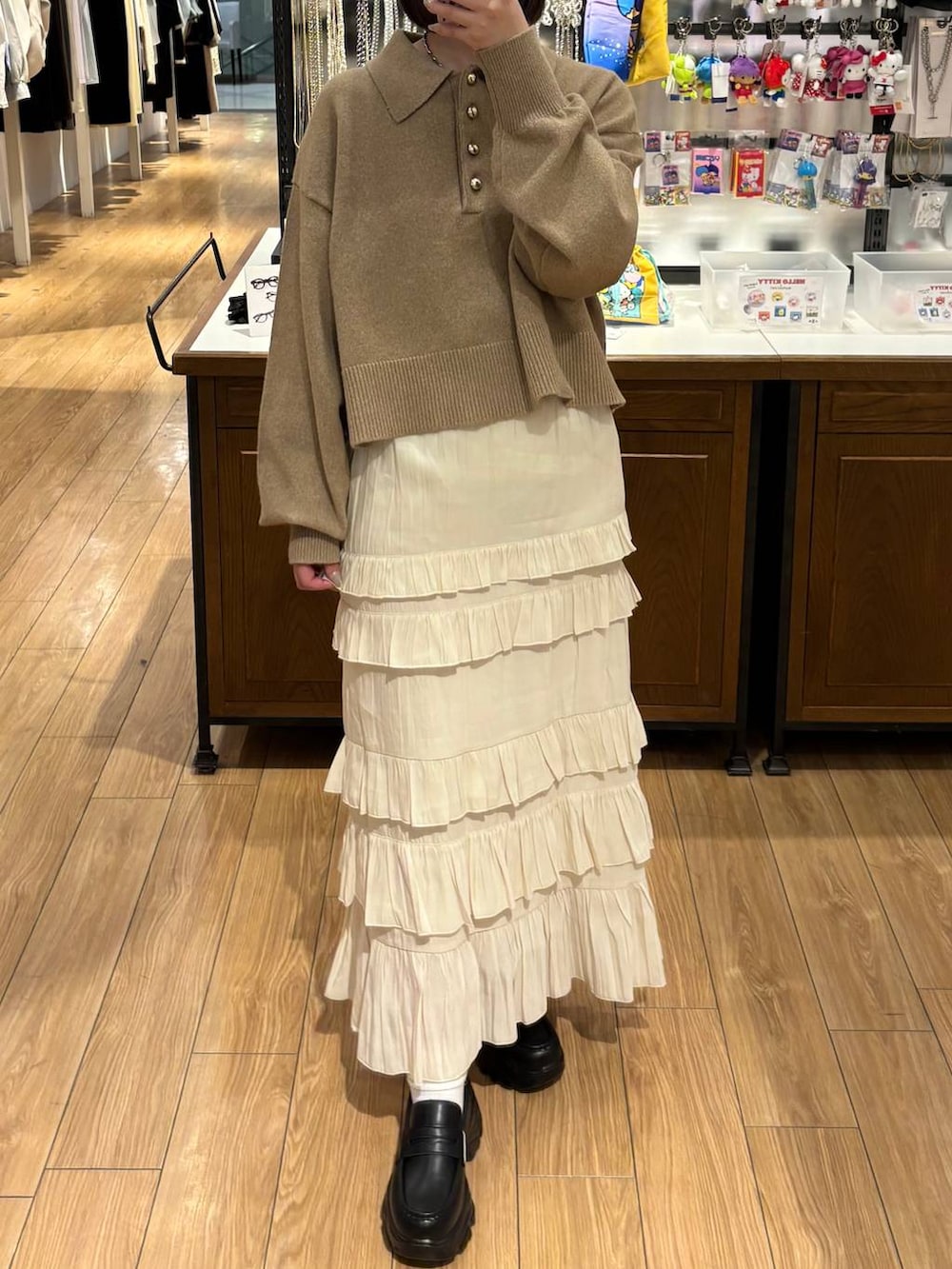 ブラック系のローファー、ホワイト系のスカート、ブラウン系のニット/セーターを着用したレディースの冬コーディネートの3枚目の写真