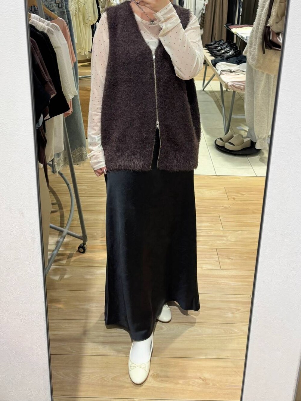 ブラック系のスカート、ブラウン系のベスト、ホワイト系のTシャツ/カットソーを着用したレディースの秋コーディネートの3枚目の写真
