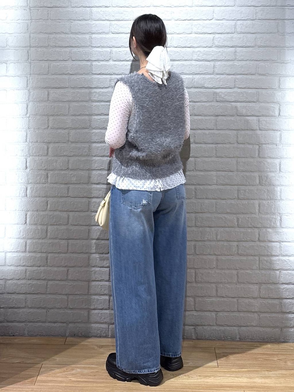 イエロー系のハンドバッグ、ホワイト系のTシャツ/カットソー、ブルー系のデニムパンツを着用したレディースの秋コーディネートの3枚目の写真
