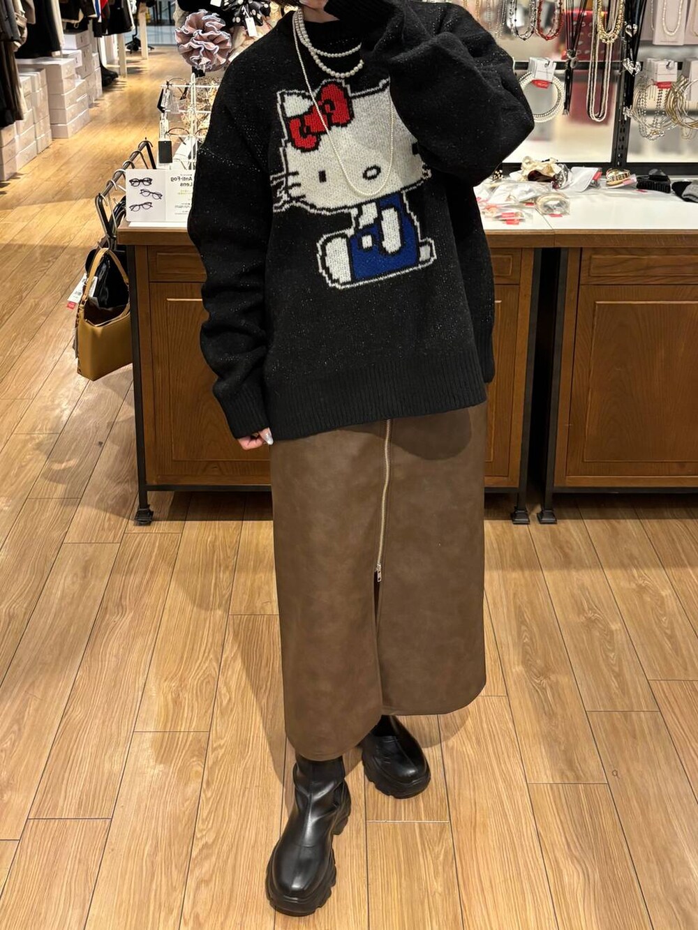 ブラウン系のスカート、ブラック系のニット/セーター、ホワイト系のネックレスを着用したレディースの秋コーディネートの3枚目の写真