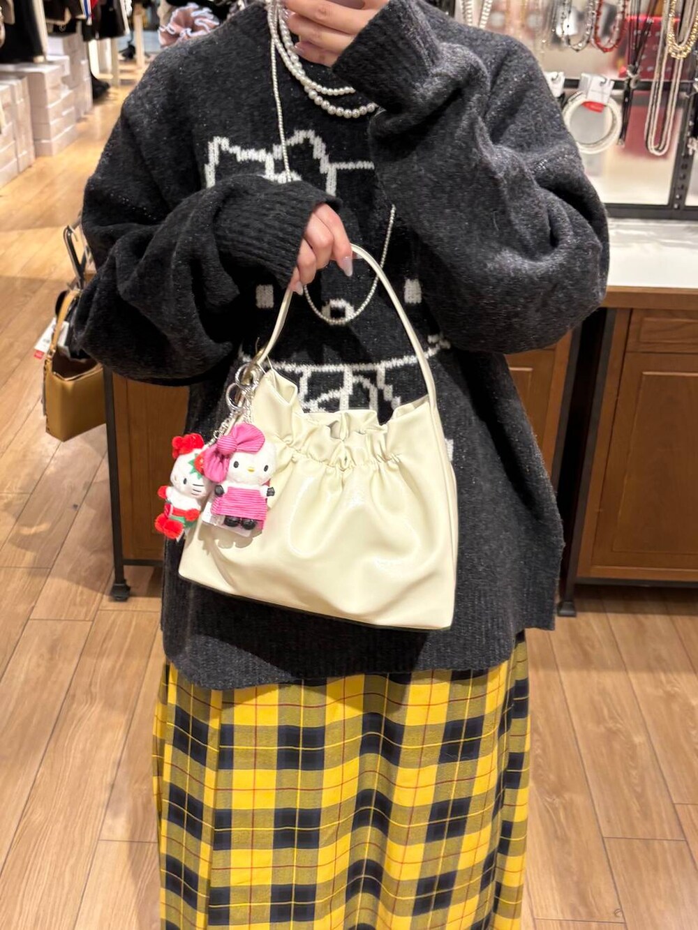 イエロー系のスカート、ホワイト系のショルダーバッグ、グレー系のニット/セーターを着用したレディースの秋コーディネートの2枚目の写真