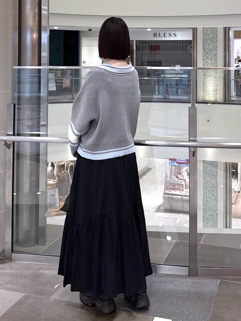 ブラック系のショルダーバッグ、ブラック系のローファー、ブラック系のスカートを着用したレディースの冬コーディネートの3枚目の写真