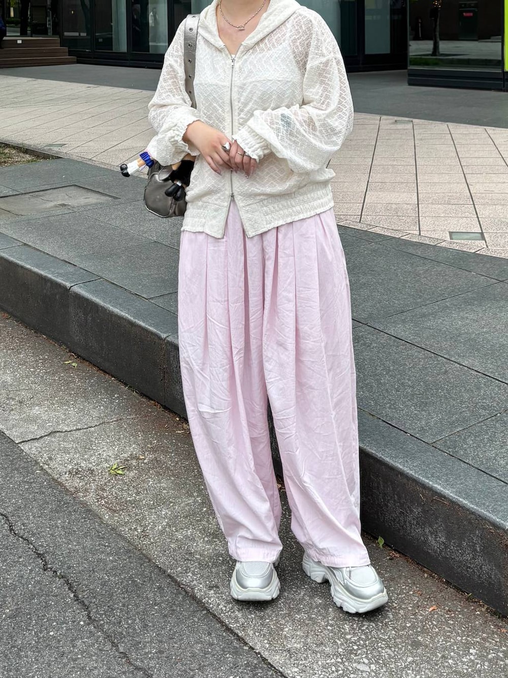 ホワイト系のパーカー、ピンク系のカーゴパンツ、シルバー系のスニーカーを着用したレディースの春コーディネートの2枚目の写真