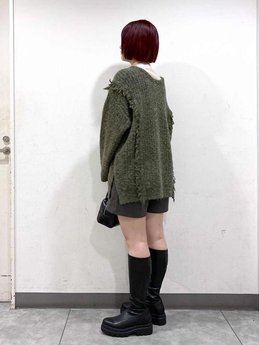 グリーン系のニット/セーター、ブラック系のブーツ、ブラック系のボストンバッグを着用したレディースの秋コーディネートの3枚目の写真