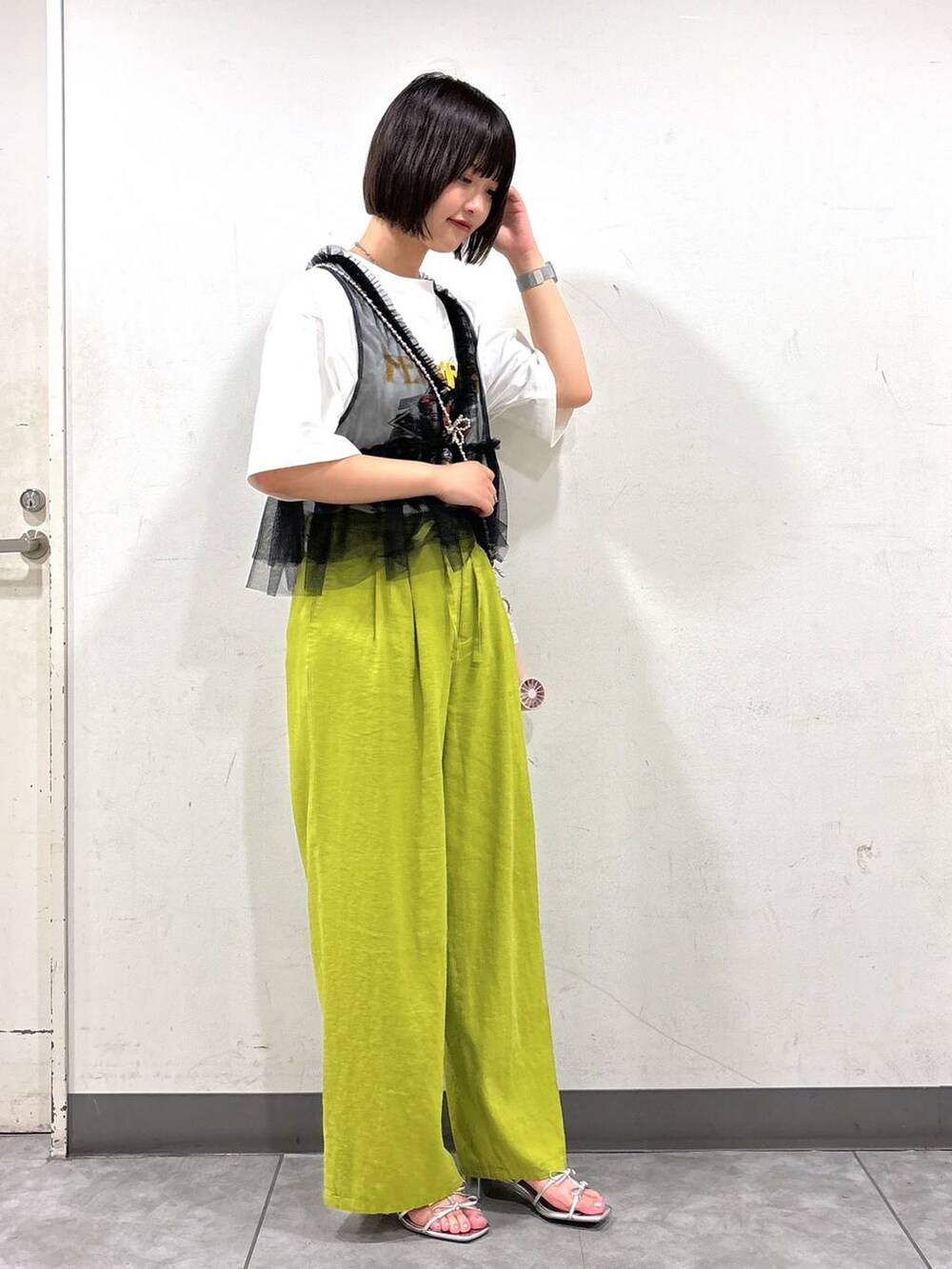 シルバー系のサンダル、グリーン系のスラックス、ホワイト系のTシャツ/カットソーを着用したレディースの夏コーディネートの2枚目の写真